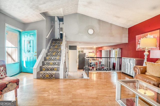 interior space featuring stairs, a textured ceiling, vaulted ceiling, and wood finished floors