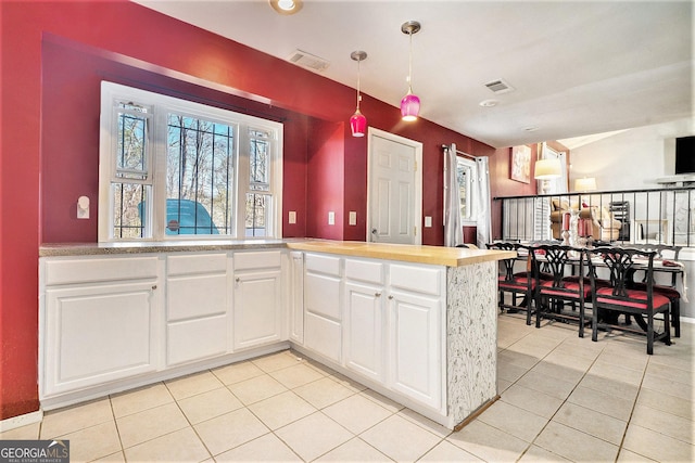 kitchen featuring light countertops, hanging light fixtures, visible vents, white cabinets, and light tile patterned flooring