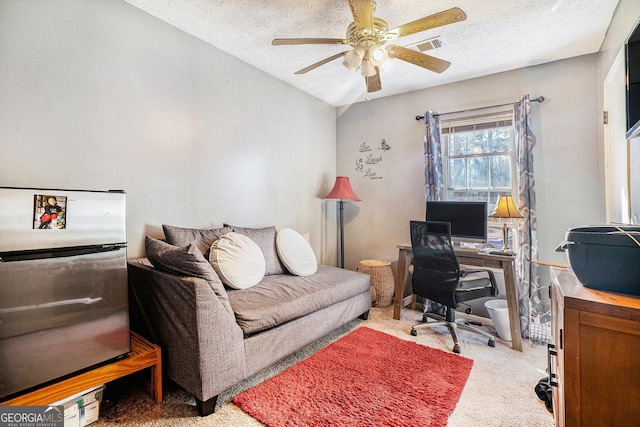 carpeted office space featuring a textured ceiling, ceiling fan, vaulted ceiling, and visible vents