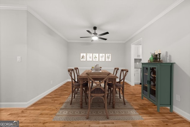 dining area with ornamental molding, light wood-type flooring, and baseboards