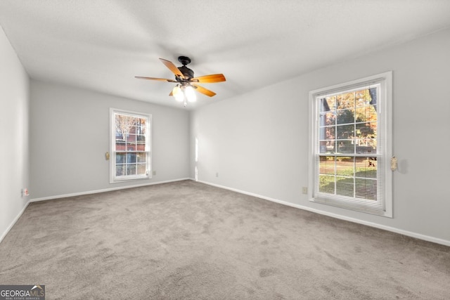 carpeted empty room with baseboards and a ceiling fan