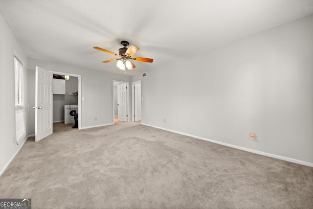 unfurnished bedroom featuring washing machine and dryer, light carpet, visible vents, baseboards, and a spacious closet