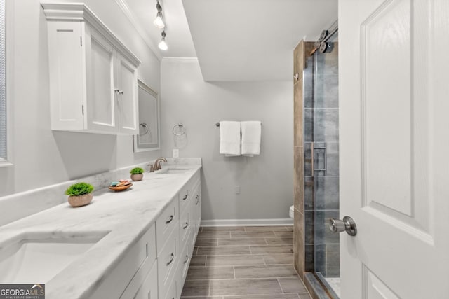 full bath with a sink, baseboards, wood tiled floor, double vanity, and a stall shower