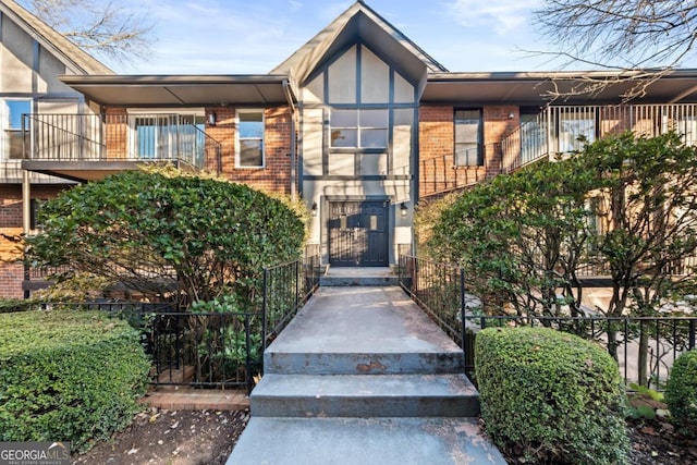 view of exterior entry with brick siding and fence