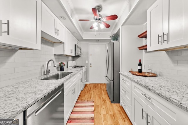 kitchen with appliances with stainless steel finishes, light stone counters, crown molding, white cabinetry, and a sink