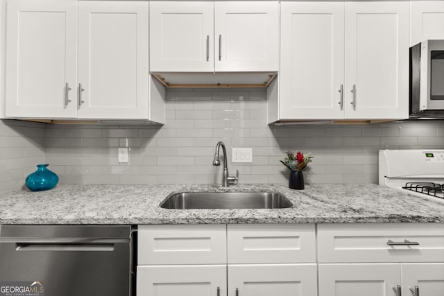 kitchen featuring light stone counters, white cabinetry, stainless steel appliances, and a sink