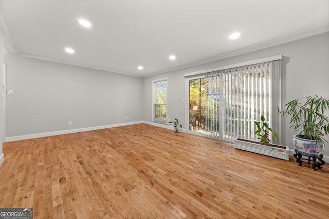 unfurnished living room with ornamental molding, light wood-type flooring, and baseboards