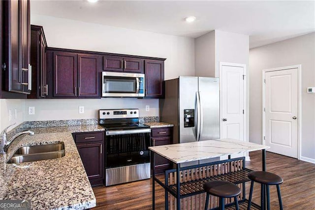 kitchen with dark wood-style floors, stainless steel appliances, a sink, and light stone countertops