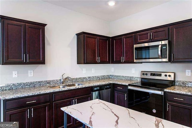 kitchen featuring stainless steel appliances, light stone counters, and a sink