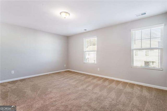 spare room with a healthy amount of sunlight, baseboards, visible vents, and carpet floors