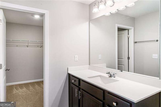 bathroom featuring vanity, baseboards, and a spacious closet