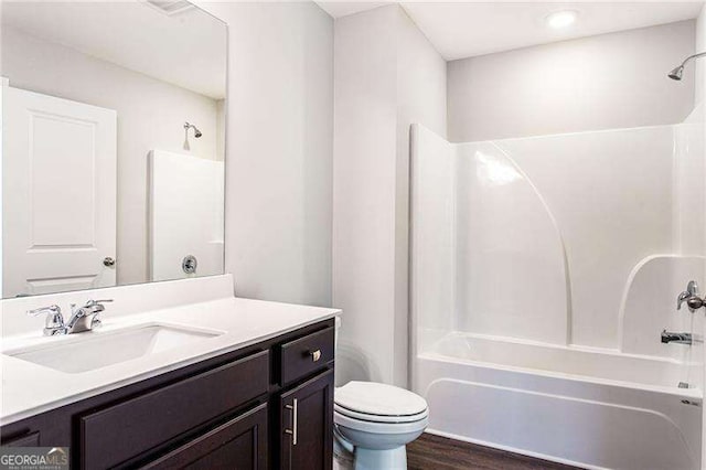 full bath with shower / bathtub combination, toilet, wood finished floors, and vanity