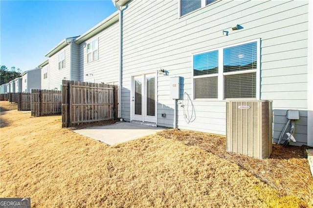 back of house featuring central AC, a patio, fence, and a lawn