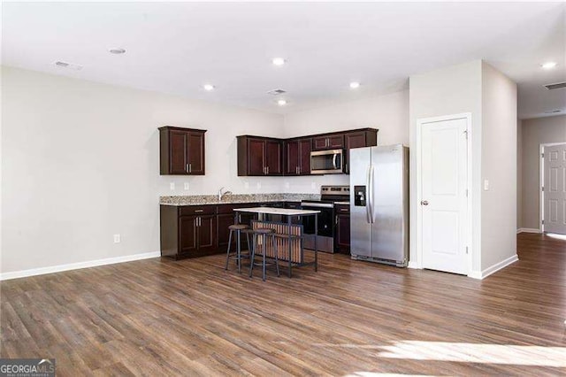 kitchen with dark brown cabinetry, a breakfast bar, a center island, stainless steel appliances, and light countertops