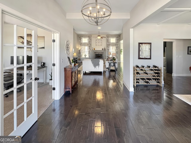 corridor with a chandelier, baseboards, and dark wood-style flooring