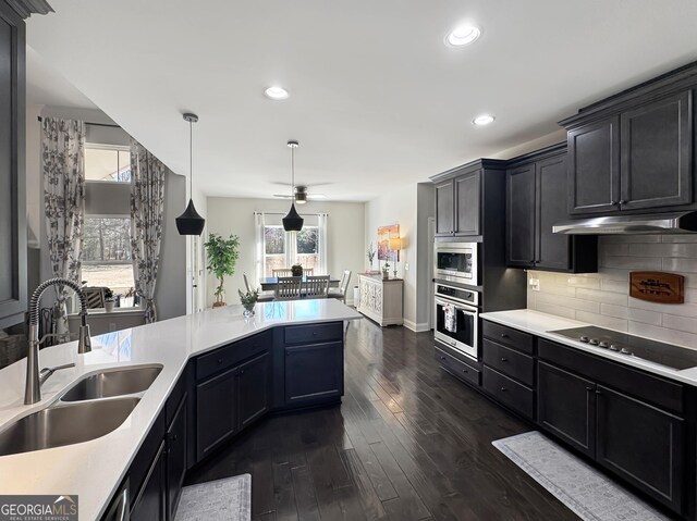 kitchen featuring custom range hood, a sink, appliances with stainless steel finishes, a peninsula, and decorative backsplash