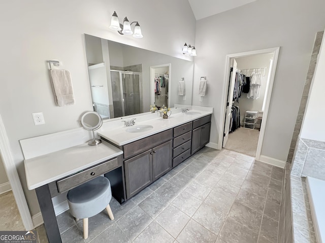 bathroom with a spacious closet, a shower stall, double vanity, and a sink