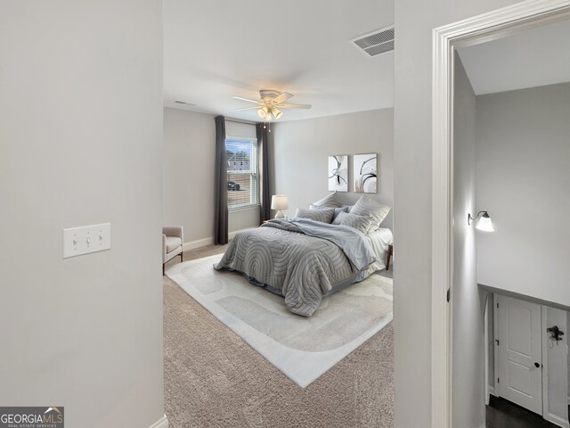 bedroom with a ceiling fan, baseboards, visible vents, and light carpet