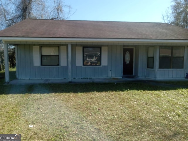 view of front of house with board and batten siding, a front yard, and a shingled roof