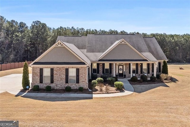 craftsman-style house with brick siding, fence, and a front yard