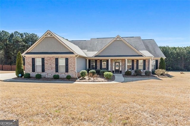 craftsman house featuring a porch, a front lawn, and brick siding