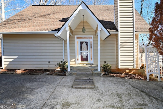 view of front of house with a shingled roof and a chimney