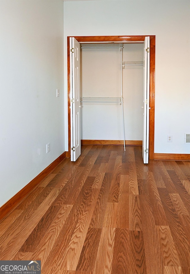 unfurnished bedroom with visible vents, a closet, baseboards, and wood finished floors