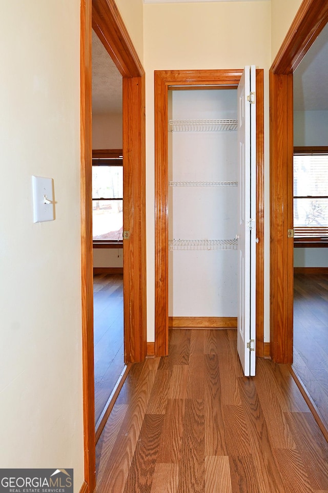 hallway featuring baseboards and wood finished floors