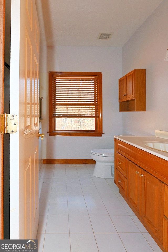 bathroom featuring visible vents, toilet, vanity, baseboards, and tile patterned floors