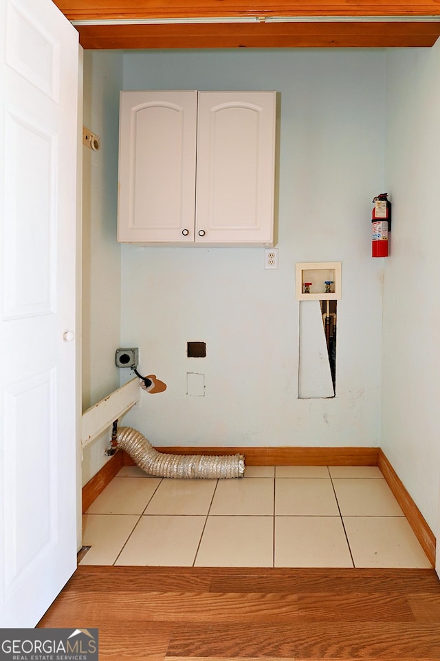 laundry room featuring light tile patterned floors, baseboards, cabinet space, and hookup for an electric dryer