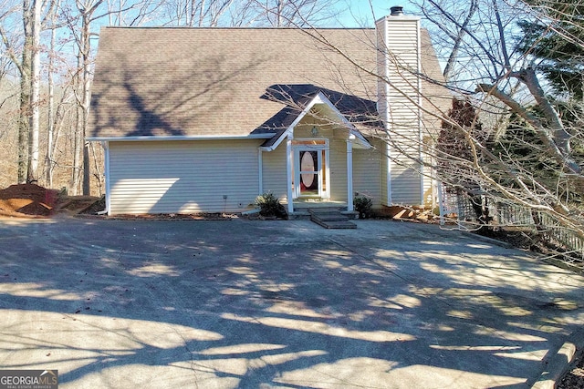 view of front facade with a chimney and roof with shingles