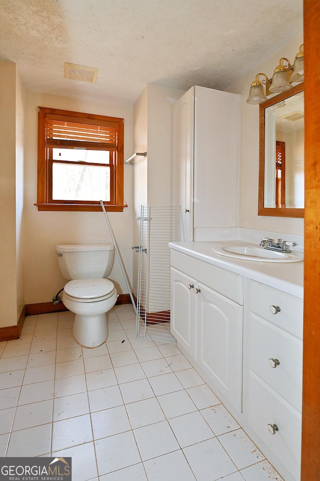 bathroom featuring a textured ceiling, toilet, vanity, visible vents, and baseboards