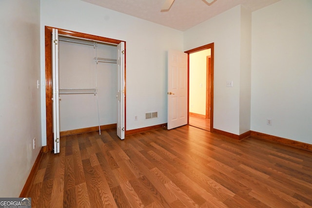 unfurnished bedroom with baseboards, visible vents, a ceiling fan, wood finished floors, and a closet