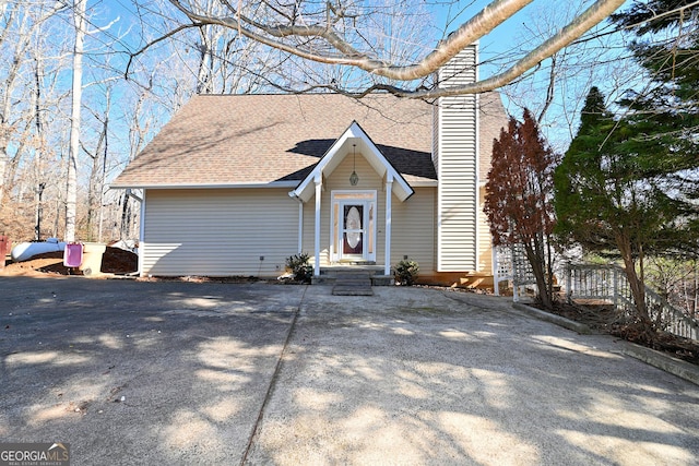 view of front of house with a shingled roof and a chimney