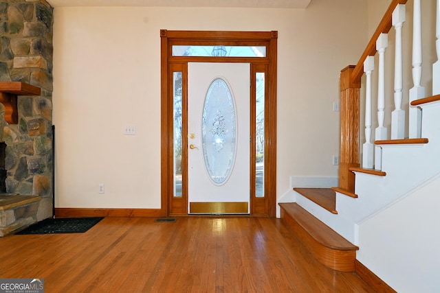 foyer with baseboards, stairs, visible vents, and wood finished floors