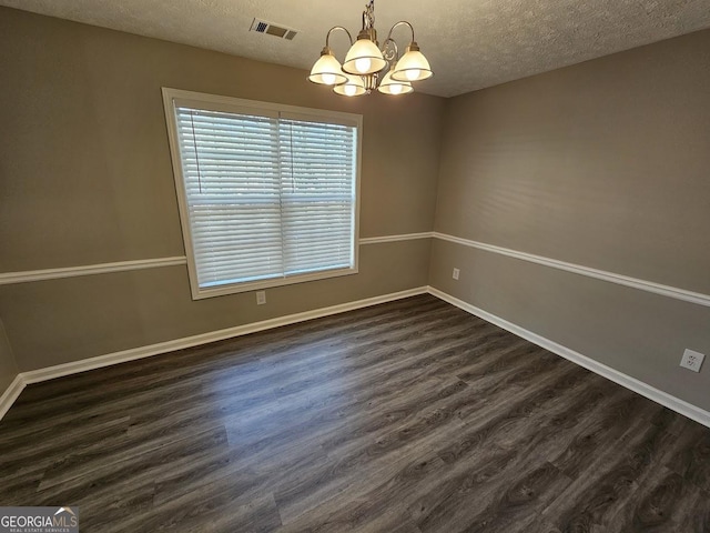 unfurnished dining area with baseboards, visible vents, dark wood finished floors, and a textured ceiling