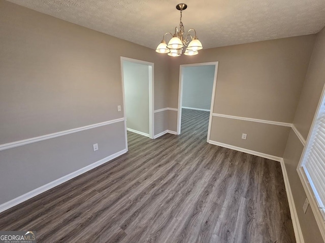 spare room with a textured ceiling, baseboards, a chandelier, and wood finished floors