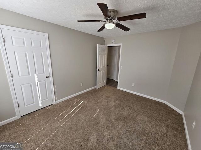 unfurnished bedroom featuring a textured ceiling, dark carpet, a ceiling fan, and baseboards