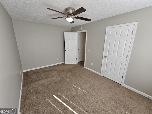 unfurnished bedroom featuring a textured ceiling, dark carpet, a ceiling fan, and baseboards