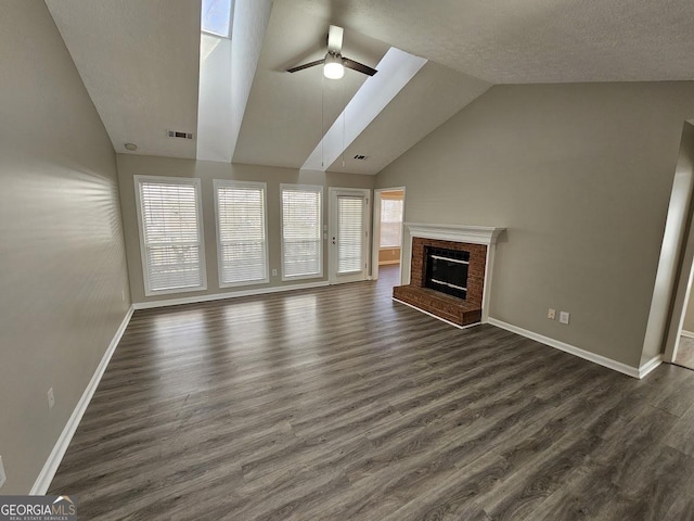 unfurnished living room featuring dark wood-style flooring, lofted ceiling, visible vents, a brick fireplace, and ceiling fan