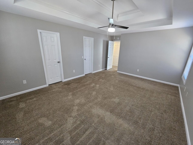 unfurnished bedroom with baseboards, a tray ceiling, and carpet flooring