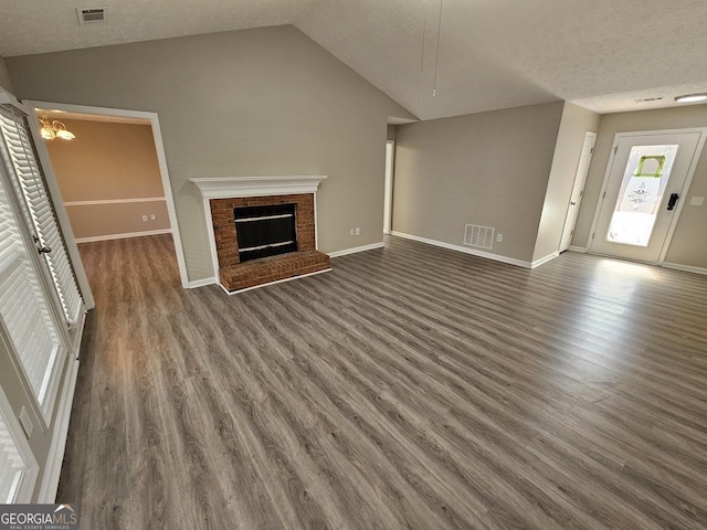 unfurnished living room featuring dark wood-type flooring, visible vents, vaulted ceiling, and a fireplace