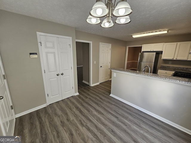 kitchen with decorative light fixtures, dark wood finished floors, freestanding refrigerator, white cabinets, and baseboards