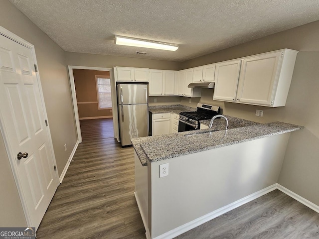 kitchen featuring a peninsula, white cabinets, stainless steel appliances, and light stone counters