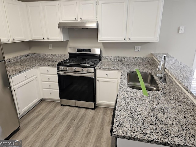 kitchen with under cabinet range hood, a sink, white cabinets, appliances with stainless steel finishes, and light stone countertops