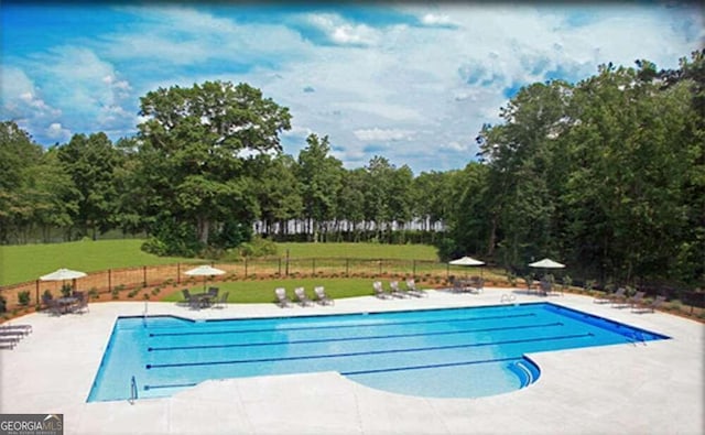 pool featuring a patio, a lawn, and fence