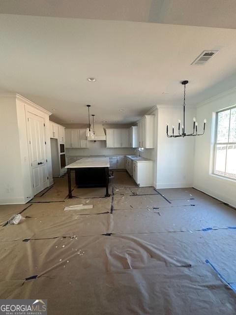 kitchen featuring baseboards, visible vents, ornamental molding, white cabinetry, and a sink