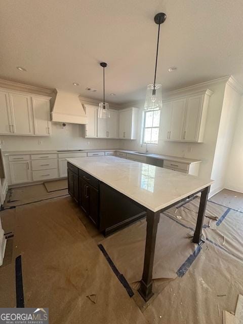 kitchen with premium range hood, a sink, white cabinetry, and pendant lighting