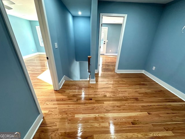 hall featuring baseboards, wood finished floors, and an upstairs landing