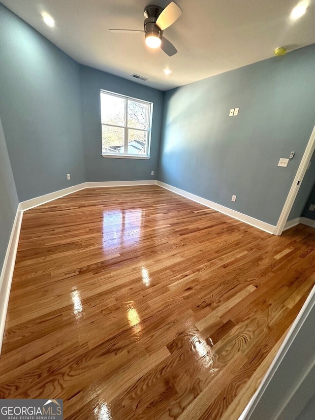 unfurnished room with visible vents, ceiling fan, baseboards, and wood finished floors